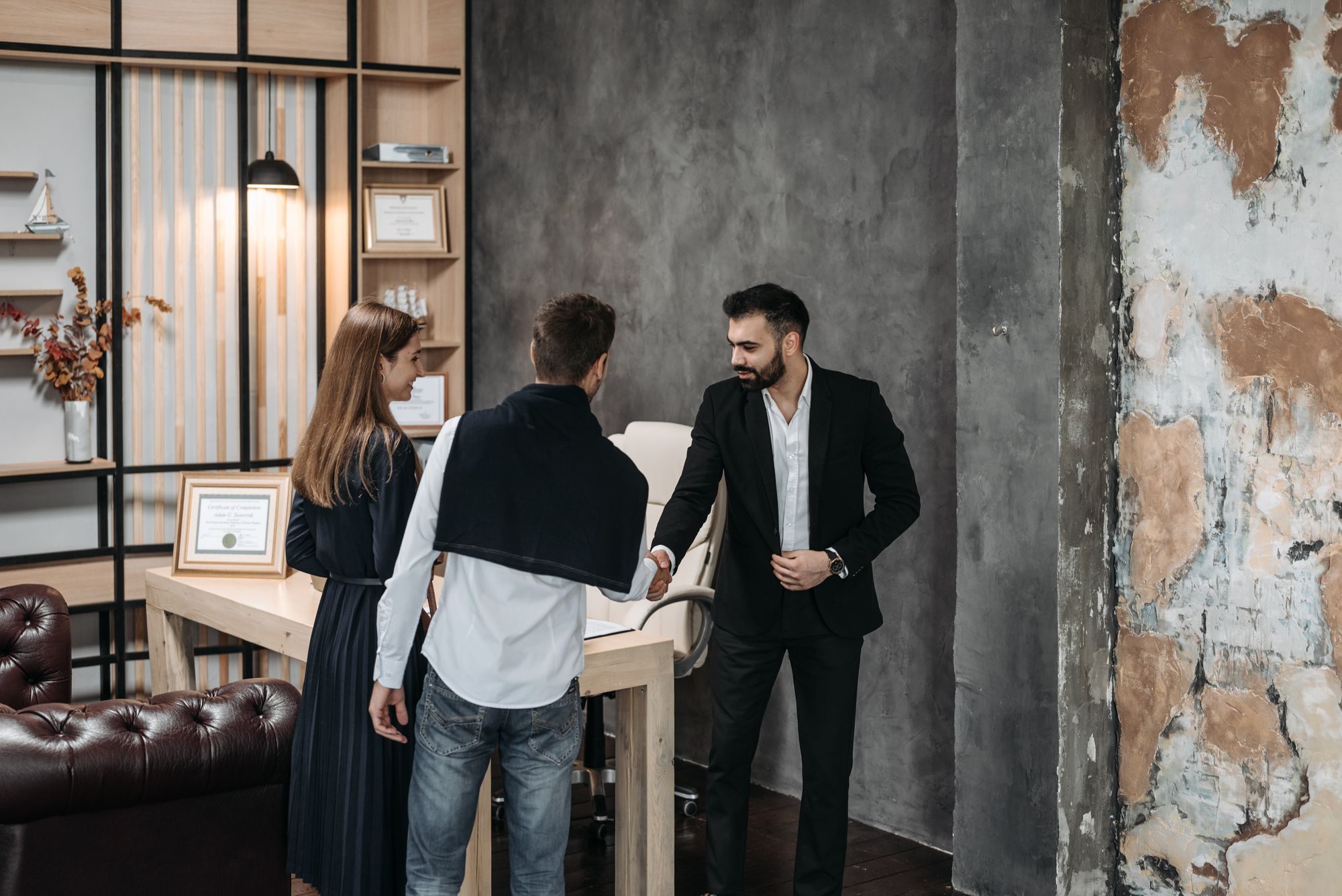 Agent shaking hands with a couple in an office